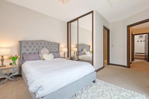 Bedroom with grey upholstered bed and mirrored wardrobes
