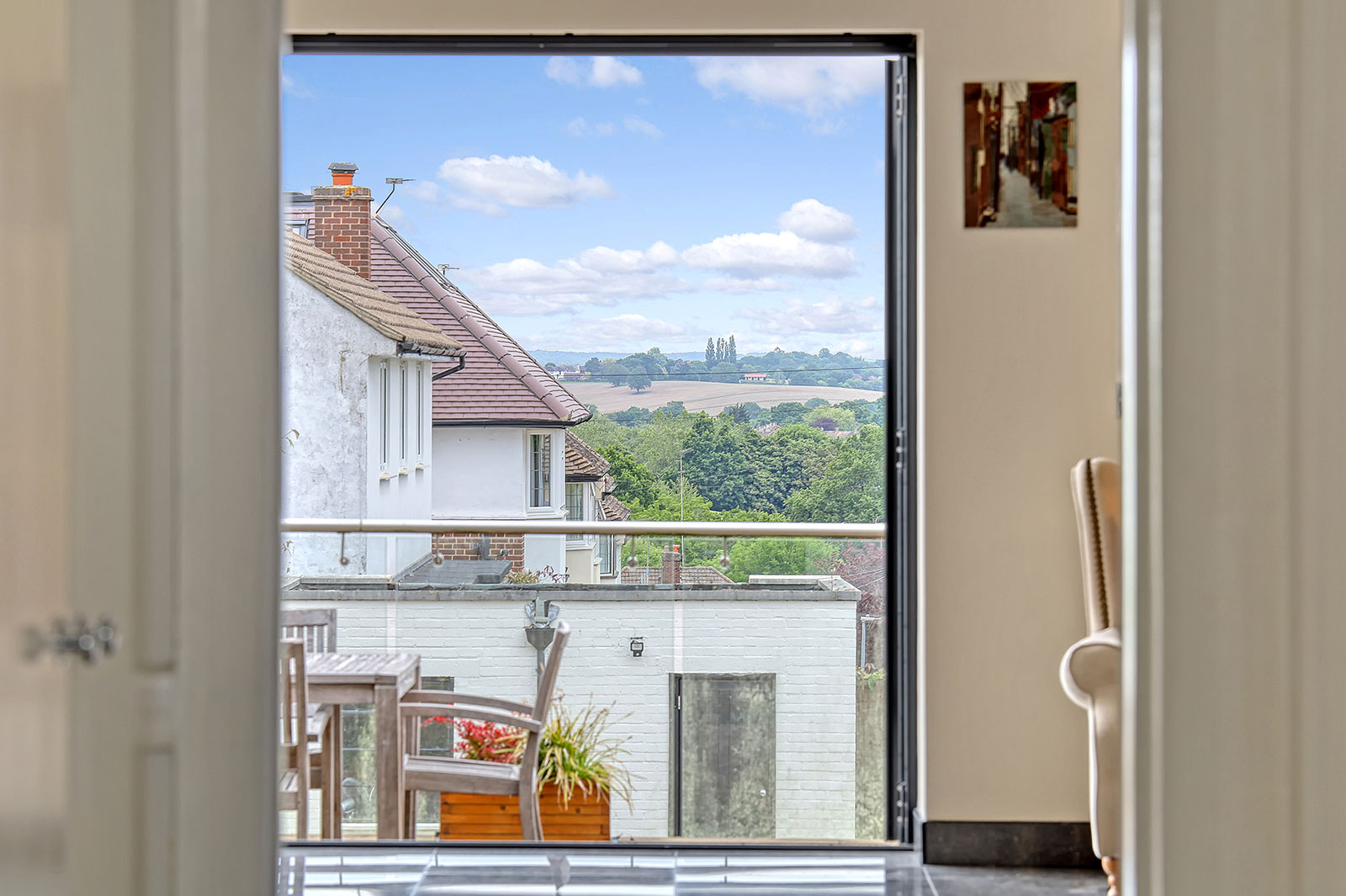 View from a balcony door over rooftops and countryside